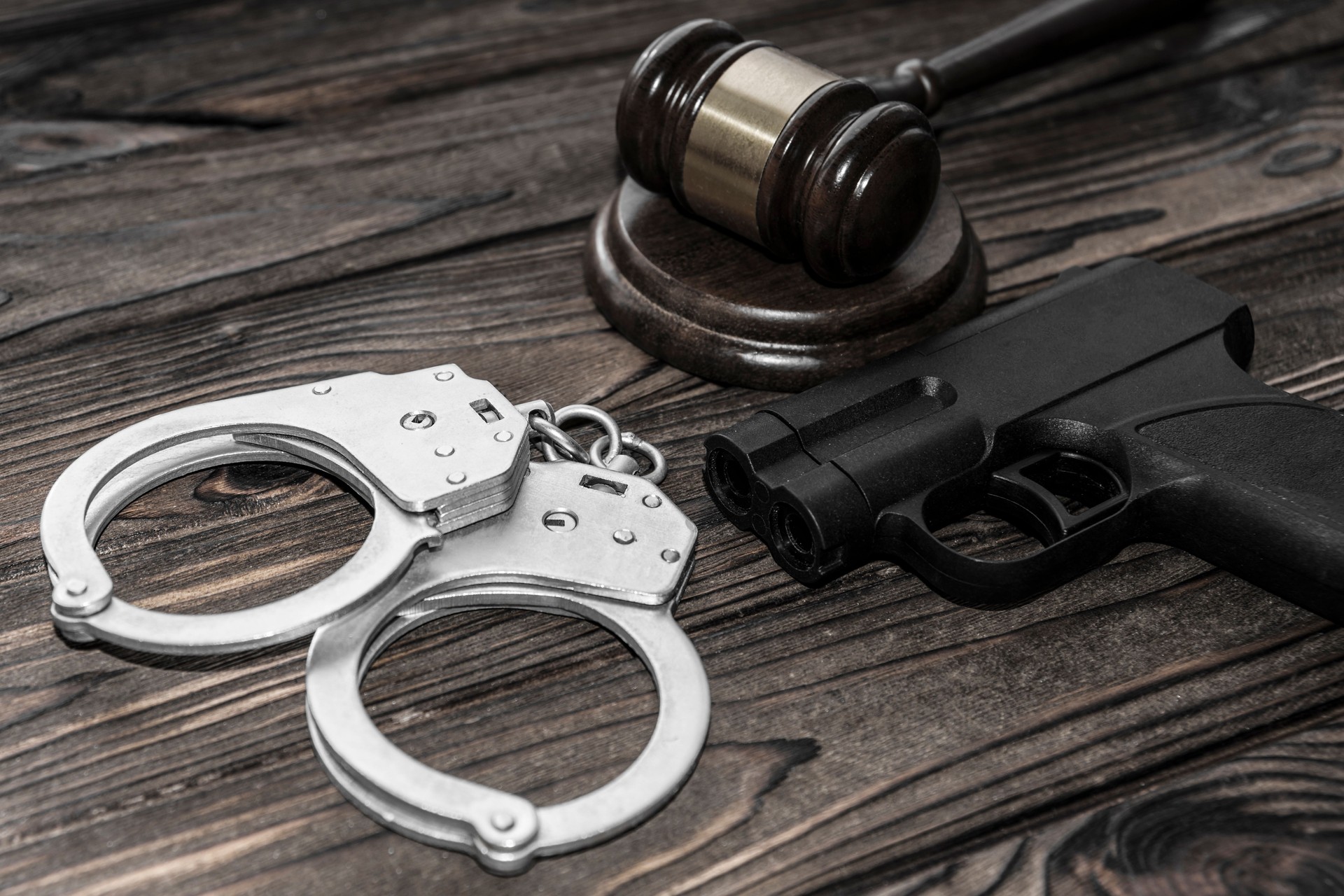 handcuffs for detaining criminals, a judge's hammer, a gun on a wooden background