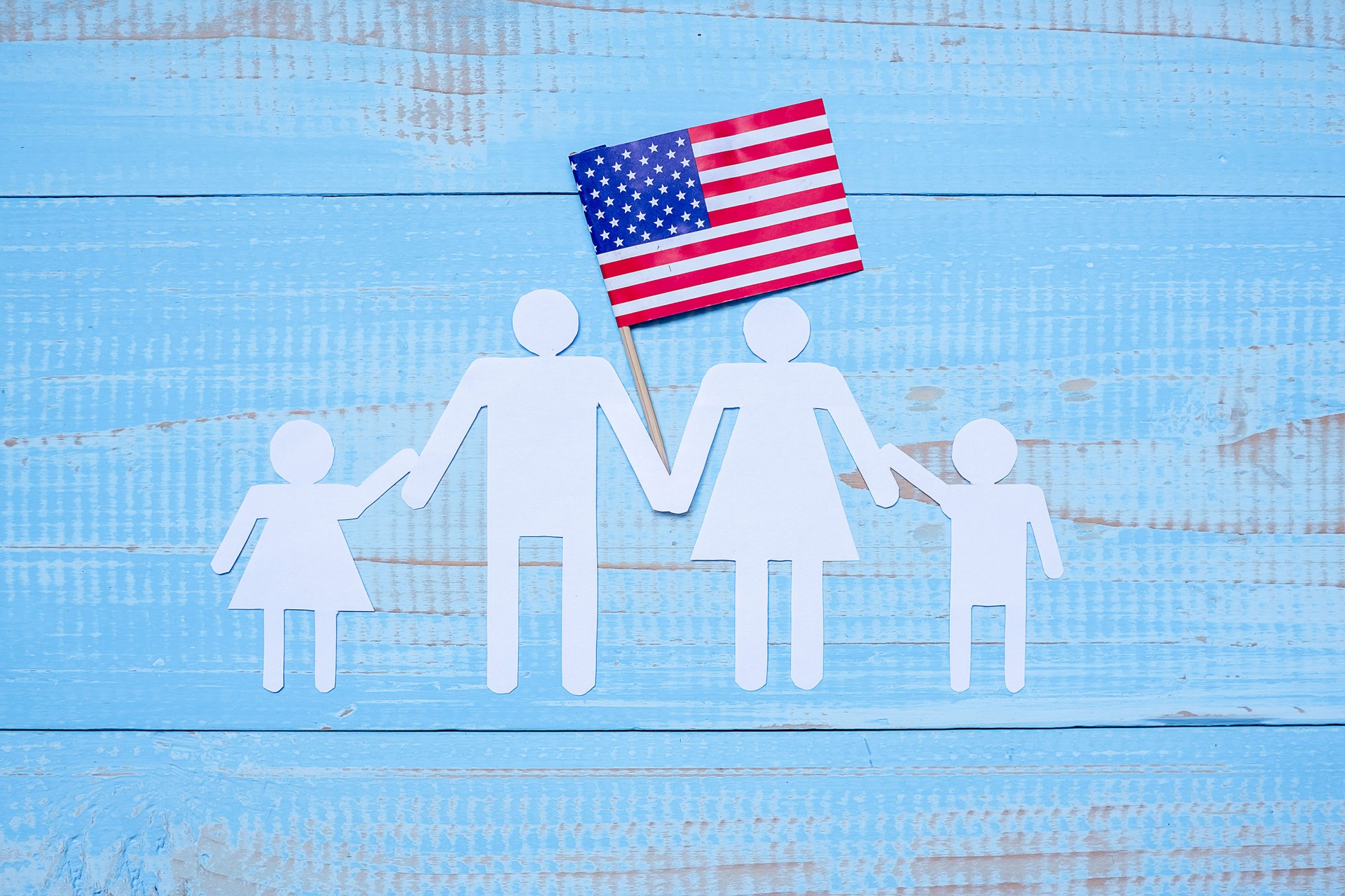People or Family paper shape with  flag of the United States of America on blue wooden background. USA holiday of Veterans, Memorial, Independence and Labor Day